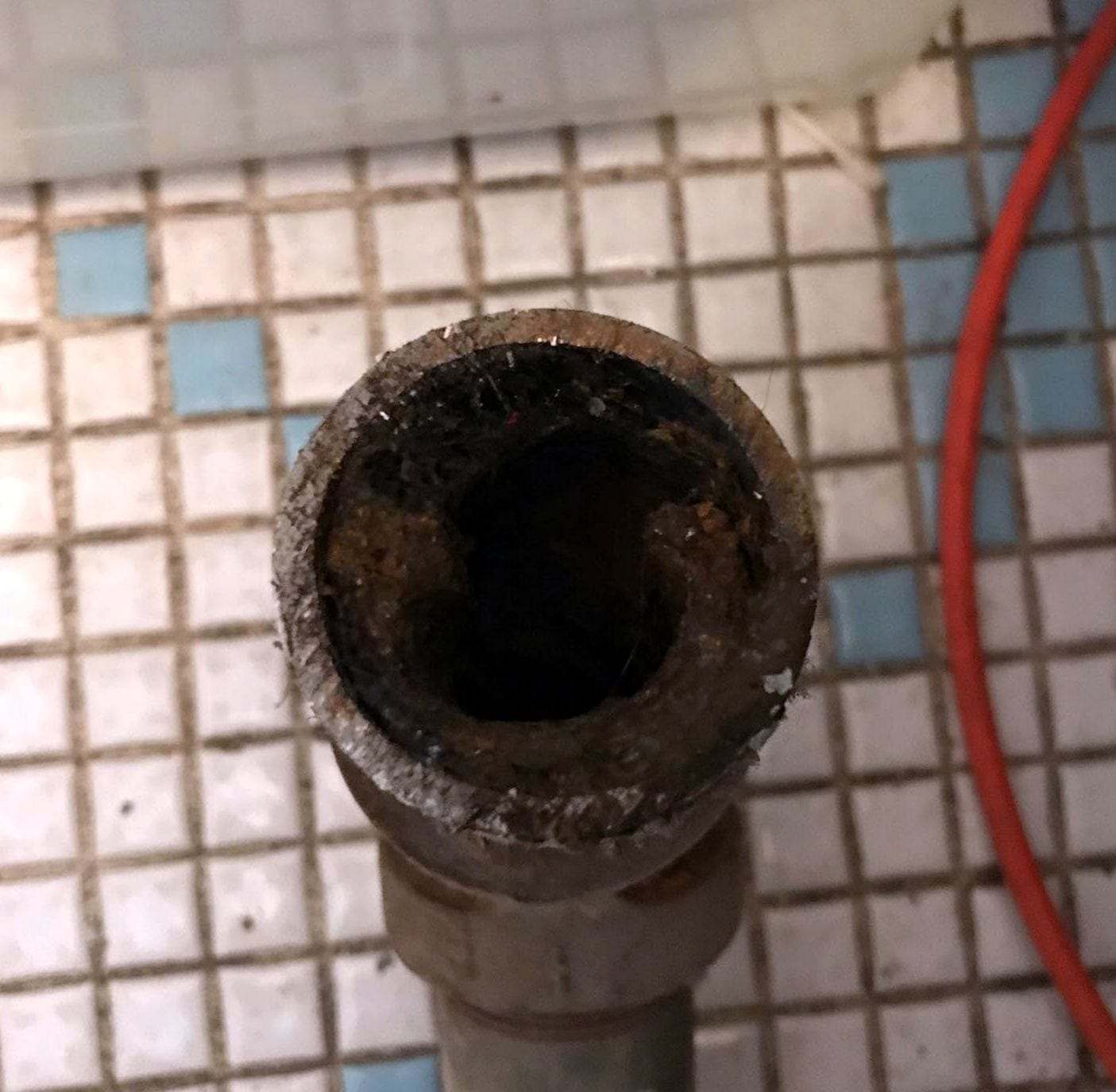 Close-up of the open end of an old pipe, its inside narrowed by rust and mineral scale