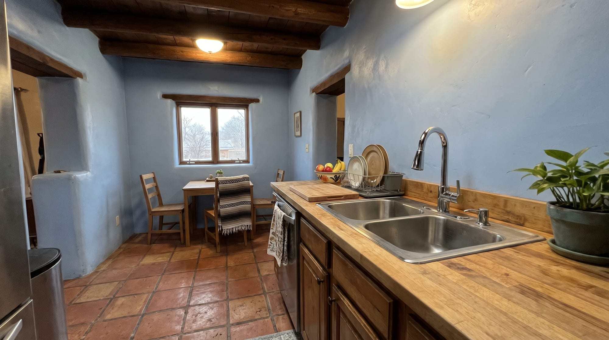 Kitchen with a chrome pull-down faucet over a double stainless sink and a wood counter